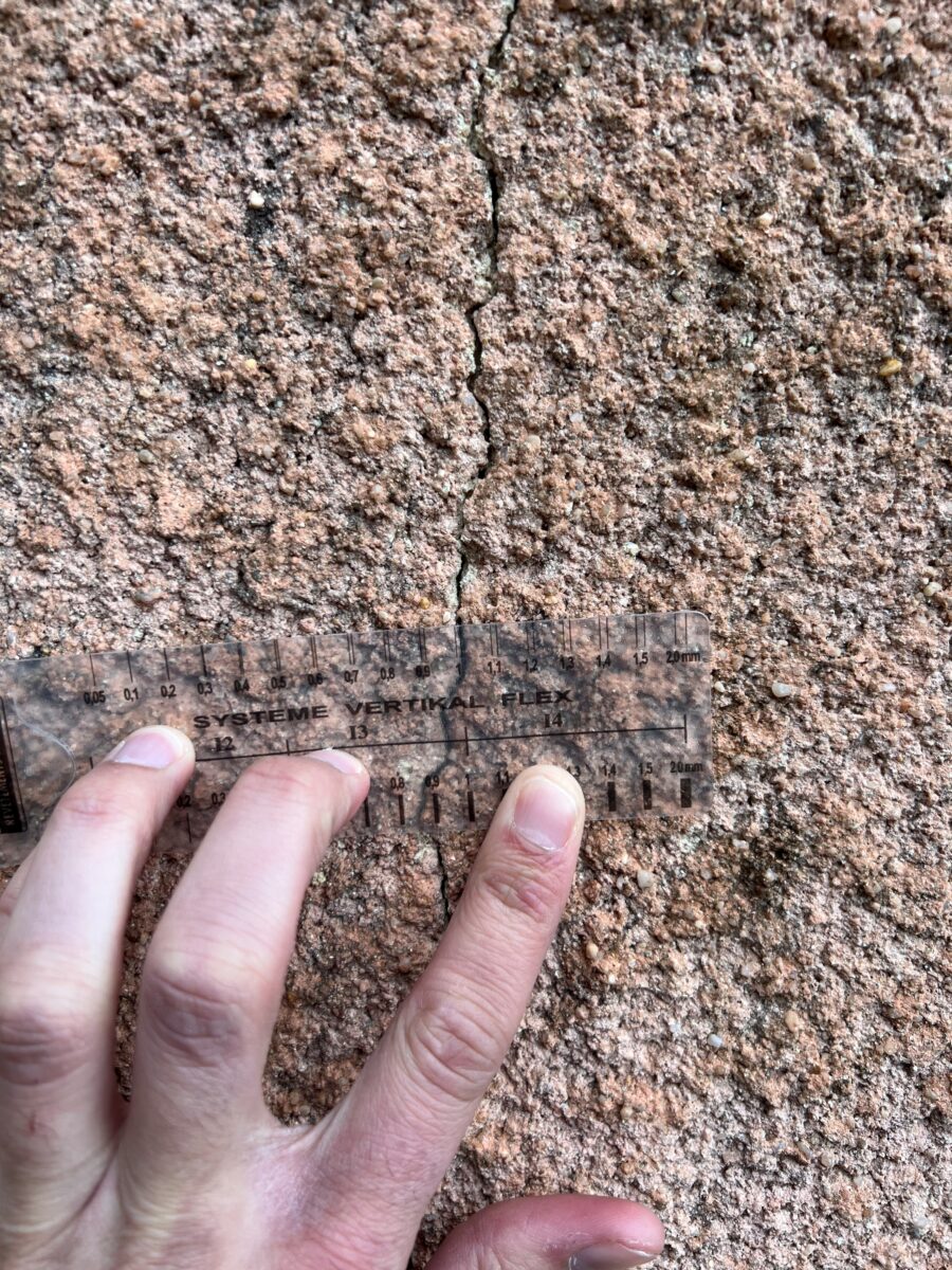 Ruler mesurant une fissure verticale sur une façade en pierre d'Espace Façades