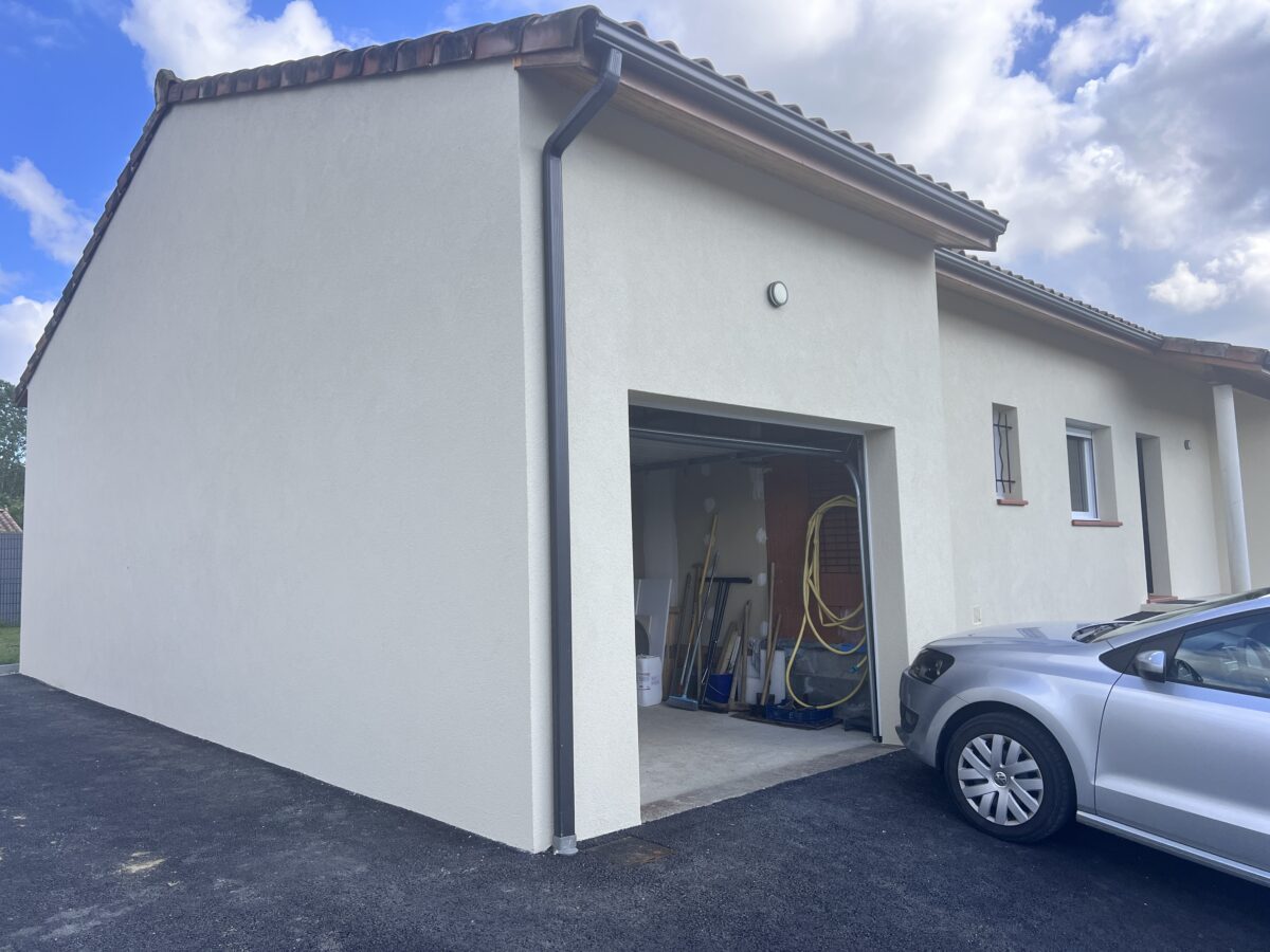 Façade de maison avec garage ouvert et équipements de jardin