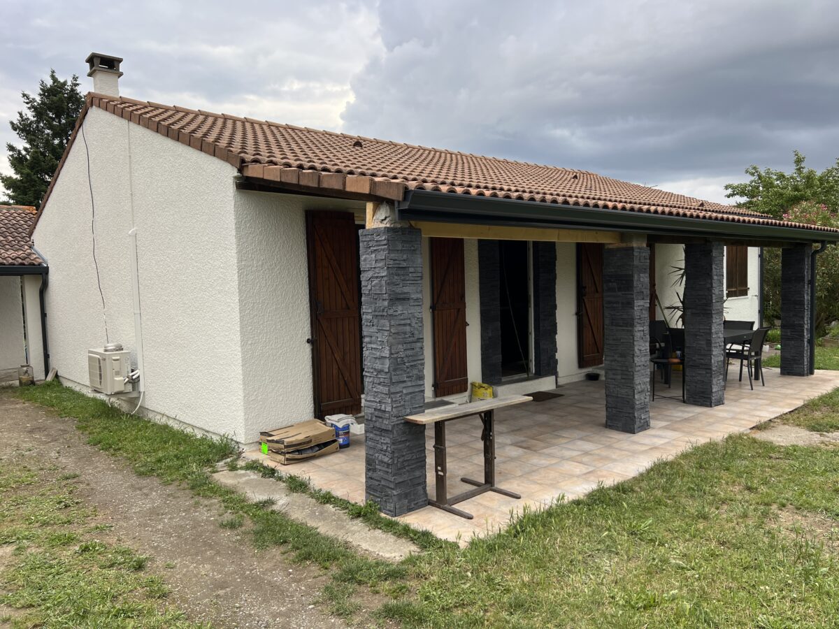 Maison avec façades blanches et pergola soutenue par des colonnes en pierre