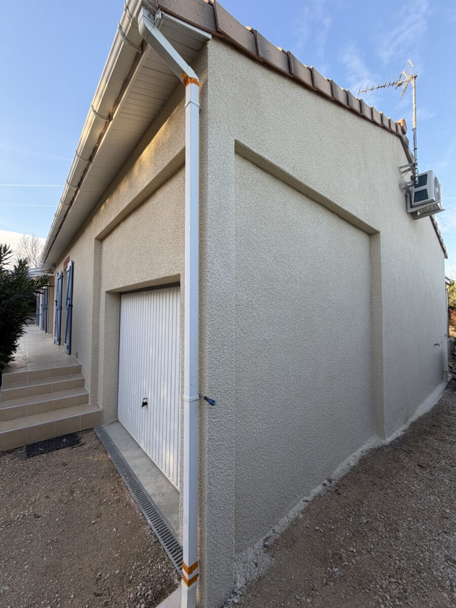 Façade de maison avec un espace de garage et système de gouttière