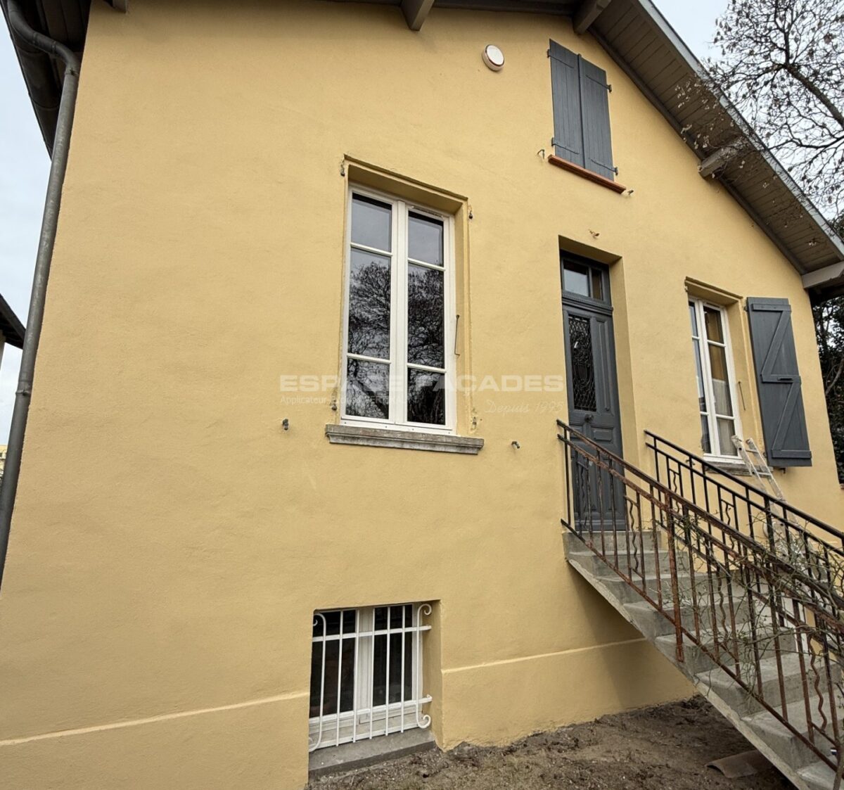 Maison jaune avec fenêtres et escaliers