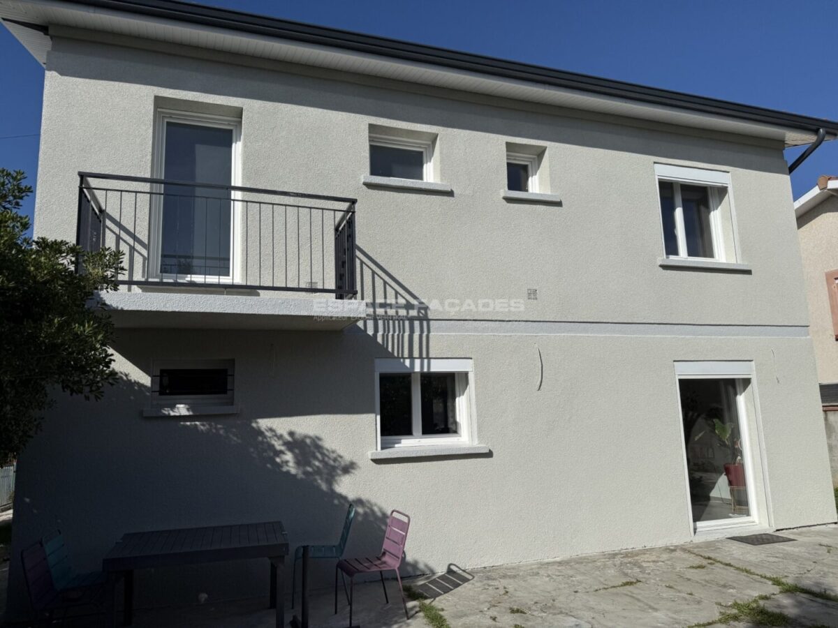 Maison à deux étages avec balcon et fenêtres.