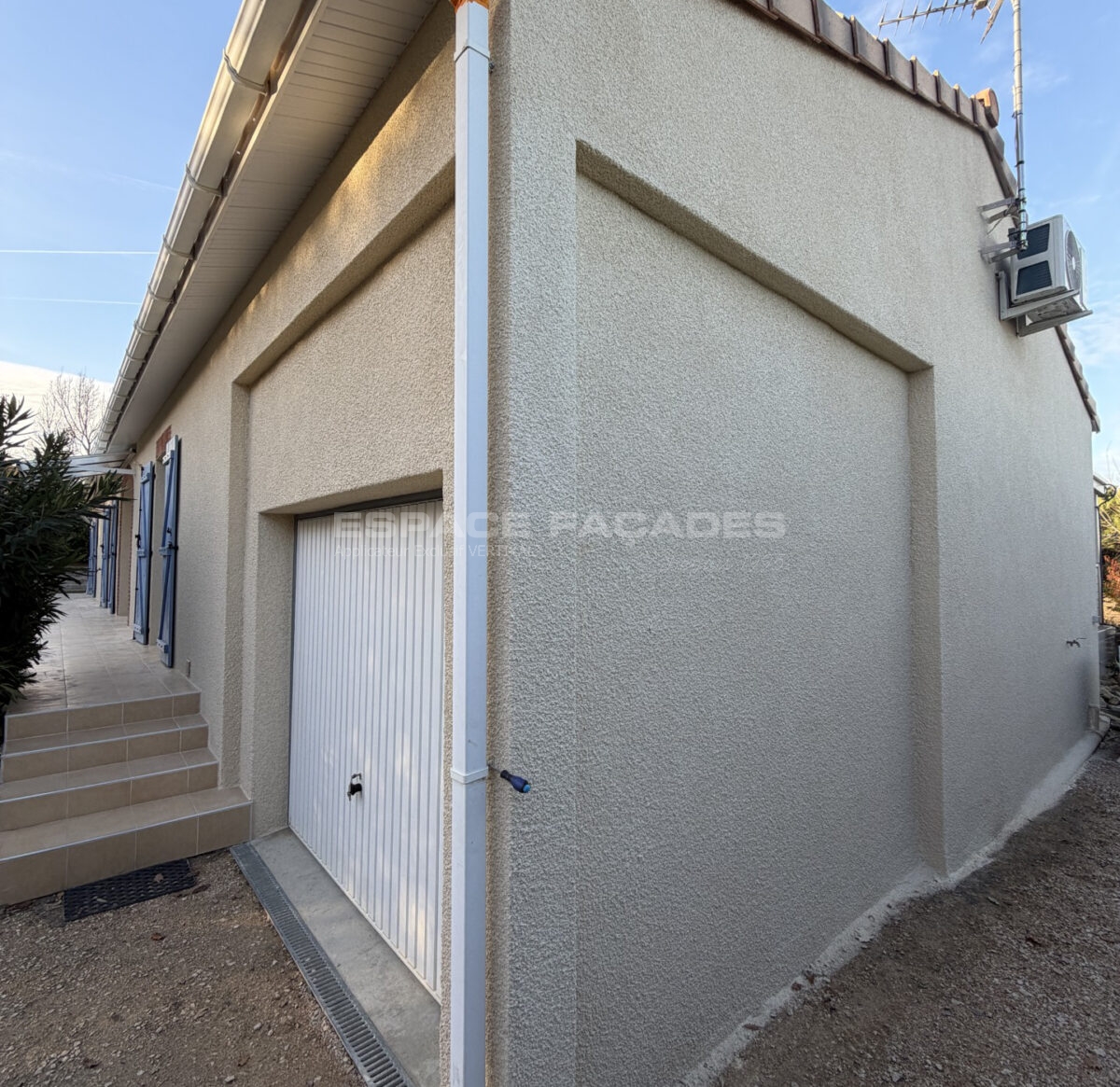 Façade d'une maison avec porte de garage et marches en céramique, espace