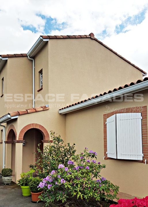 Maison avec volets blancs et fleurs colorées.