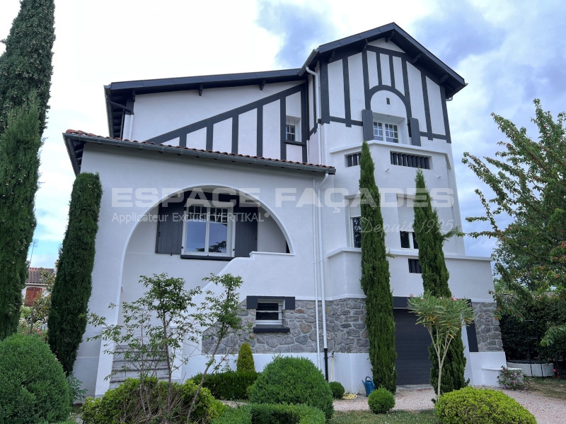 Maison à deux étages avec façade en bois et pierre, jardin.